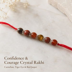 Confidence & Courage Crystal Rakhi with Carnelian and Tiger Eye beside festive diya ā Bellarosa Gems